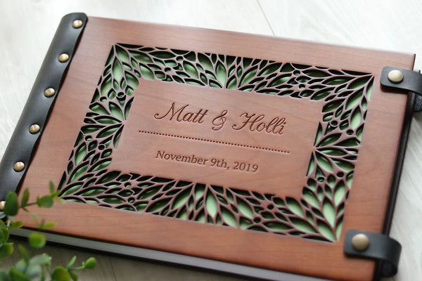 Personalized wooden wedding photo album with floral cutout cover, leather binding, and engraved names and date