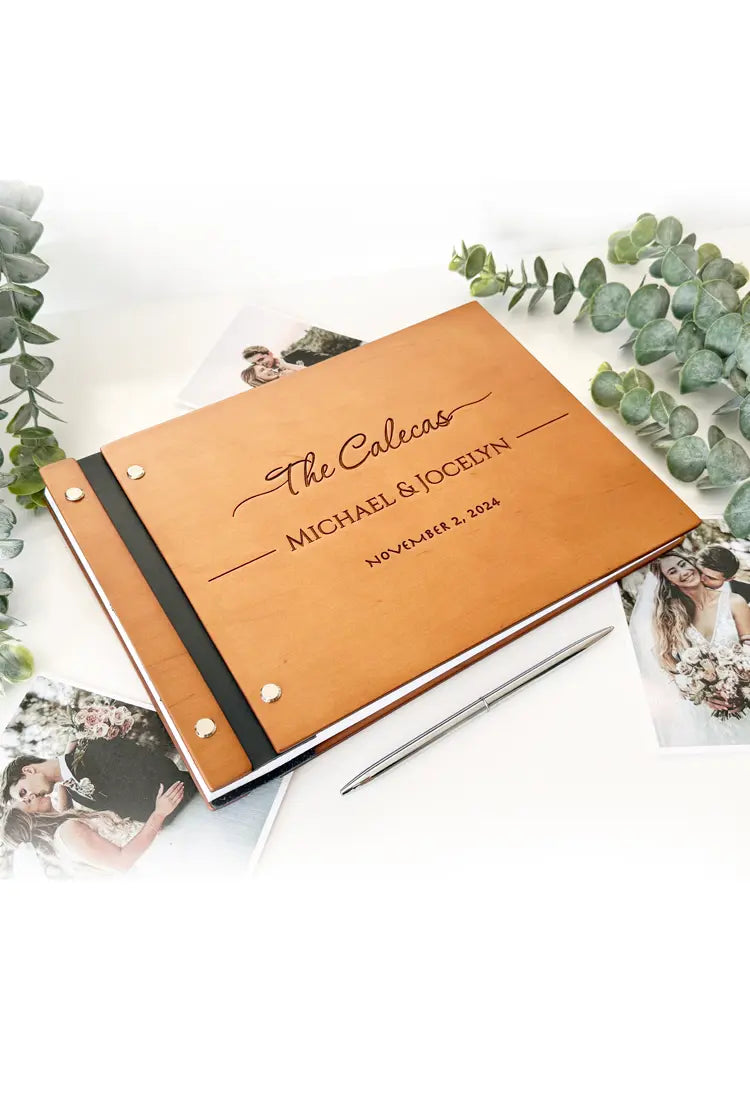Personalized photo album with engraved text on a white surface with greenery and photos.