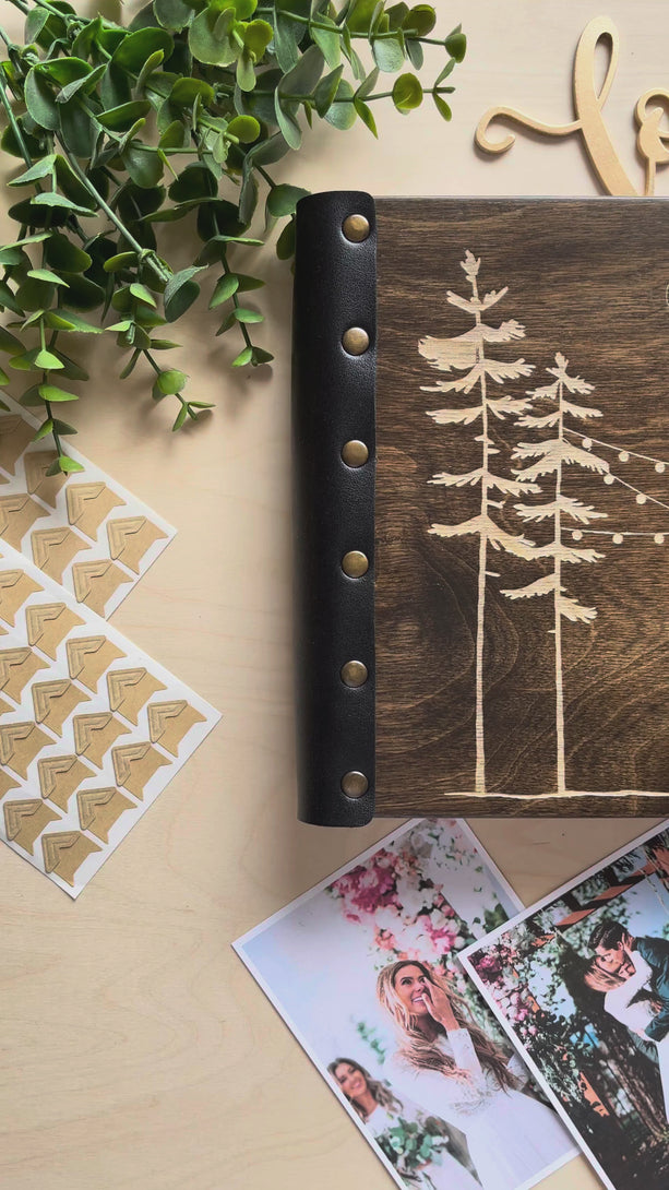 forest wedding photo album engraved with pine trees string lights and couple